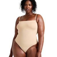 Woman wearing a beige swimsuit against a plain background